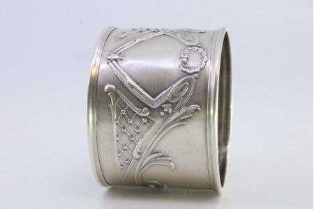 Argola de guardanapo em prata com motivos florais relevados e frisos nos bordos.